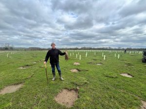 picture of the owner of Sandlands holding up some saplings about to be planted